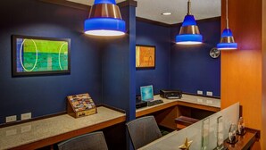 A modern office space with blue walls, a desk with a computer, and two blue pendant lights. - Fairfield Inn & Suites by Marriott Indianapolis Noblesville (Noblesville)