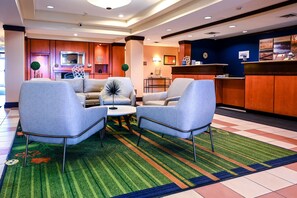 Un hall d’entrée avec deux fauteuils, une table basse, un comptoir de réception et une cheminée.