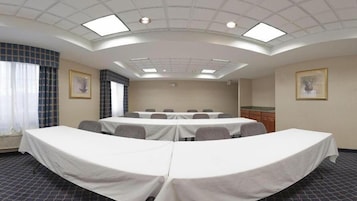 A conference room with a long table, multiple chairs, and a kitchenette area.
