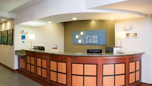 Un comptoir d’accueil incurvé, doté d’une horloge numérique, d’une enseigne Holiday Inn Express et d’une horloge murale.