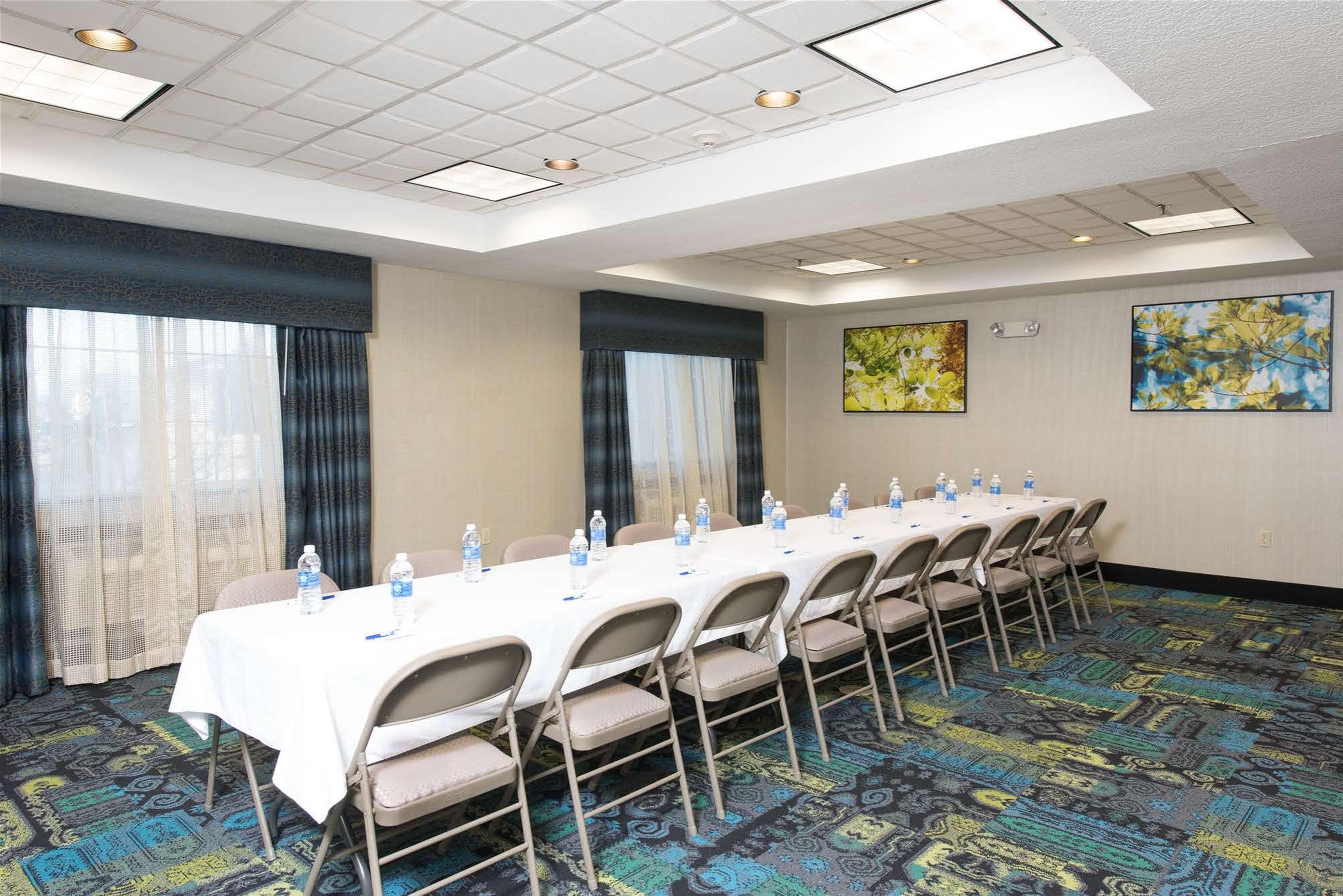 A conference room with a long table, chairs, water bottles, and two paintings on the walls.