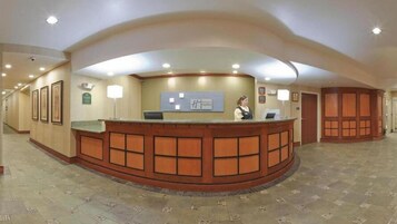 A reception area with a curved wooden reception desk, a receptionist, and a sign above the desk.