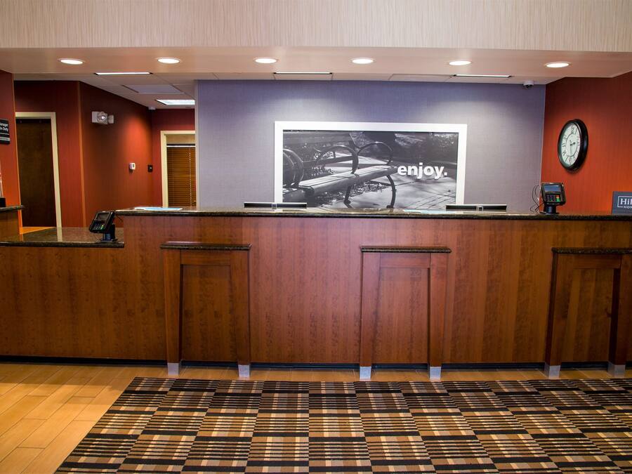 Una reception di hotel con una sveglia, un telefono digitale e una segnaletica con il marchio Hilton.
