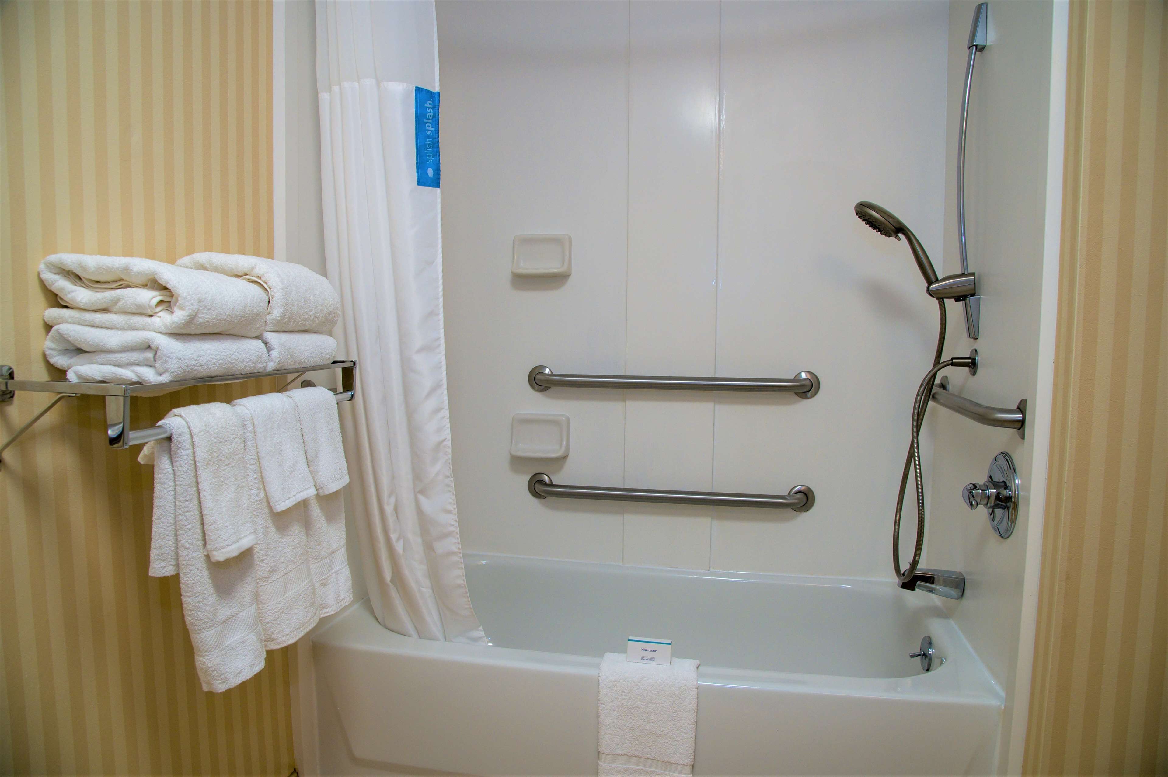 A bathroom with a bathtub, a shower, and a towel rack with folded towels.