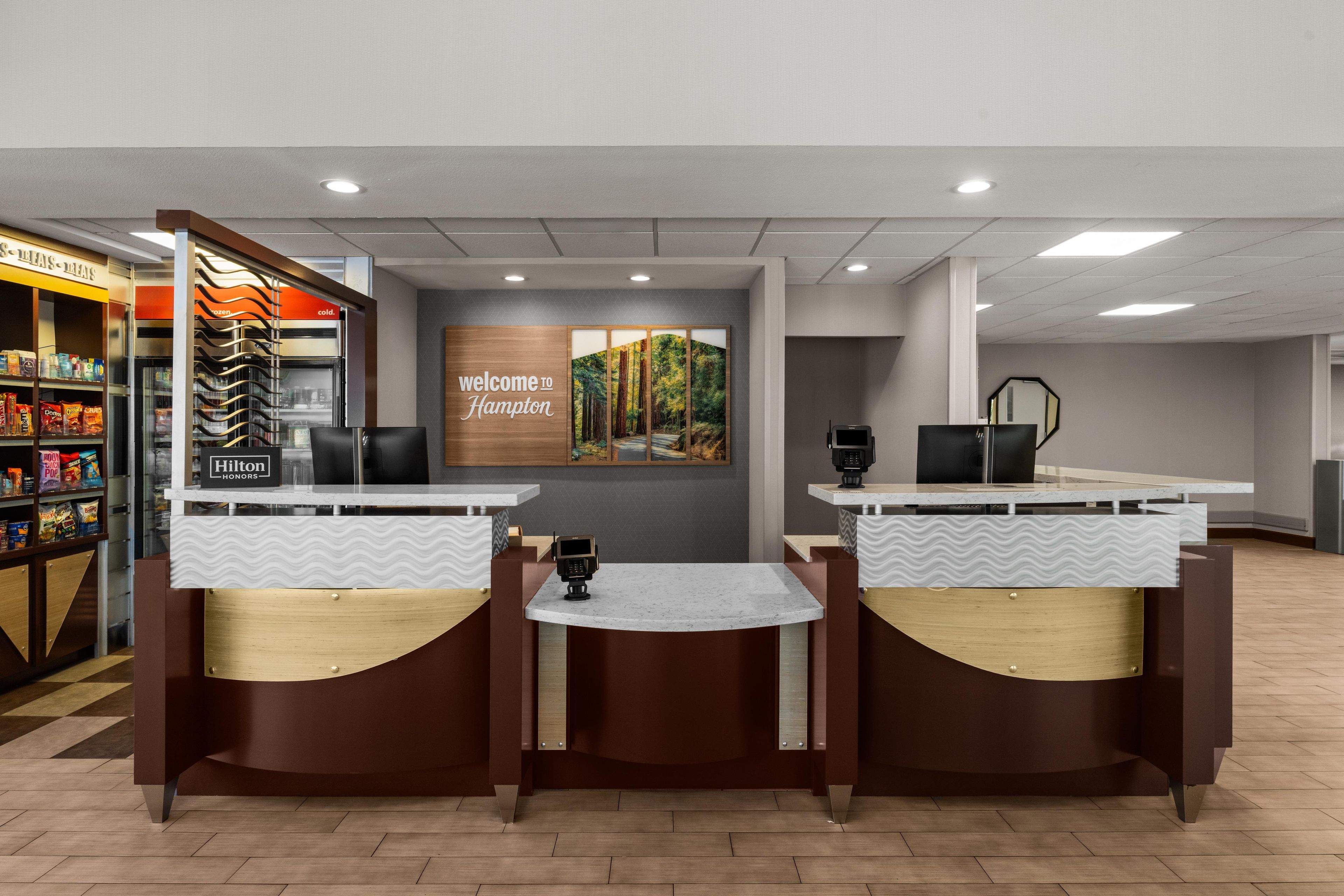 Un espace d’accueil d’hôtel avec un panneau d’accueil, un distributeur automatique et une machine à café.
