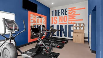 Une salle de sport équipée de matériel d’exercice, dotée d’un mur d’inspiration et d’un meuble de rangement.