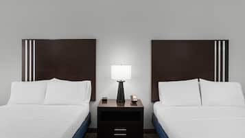 A hotel room with two beds, a nightstand with a lamp, and a drawer.