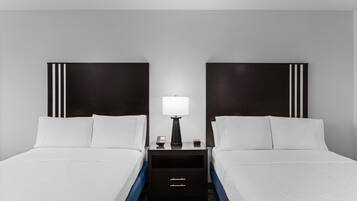 Une chambre d’hôtel avec deux lits, une table de chevet avec une lampe et une commode.