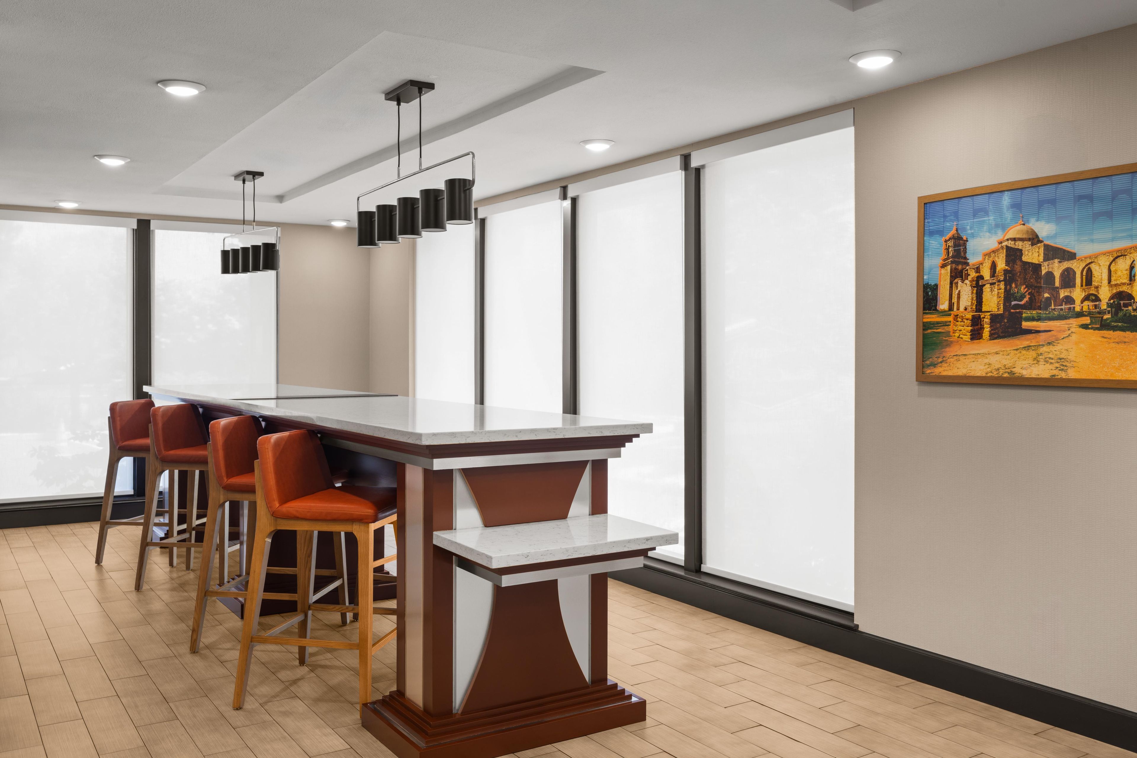 Un espace bar moderne avec un comptoir en marbre, des tabourets en bois et des luminaires suspendus.