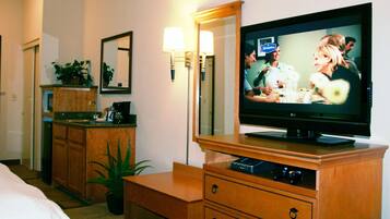 Una habitación de hotel con televisión, muebles de madera, un espejo y una planta en maceta.