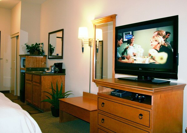 A hotel room with a television, wooden furniture, a mirror, and a potted plant. - Hampton Inn & Suites Mountain View (Mountain View)