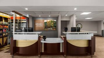 Un espace d’accueil d’hôtel avec un panneau d’accueil, un distributeur automatique et une machine à café.