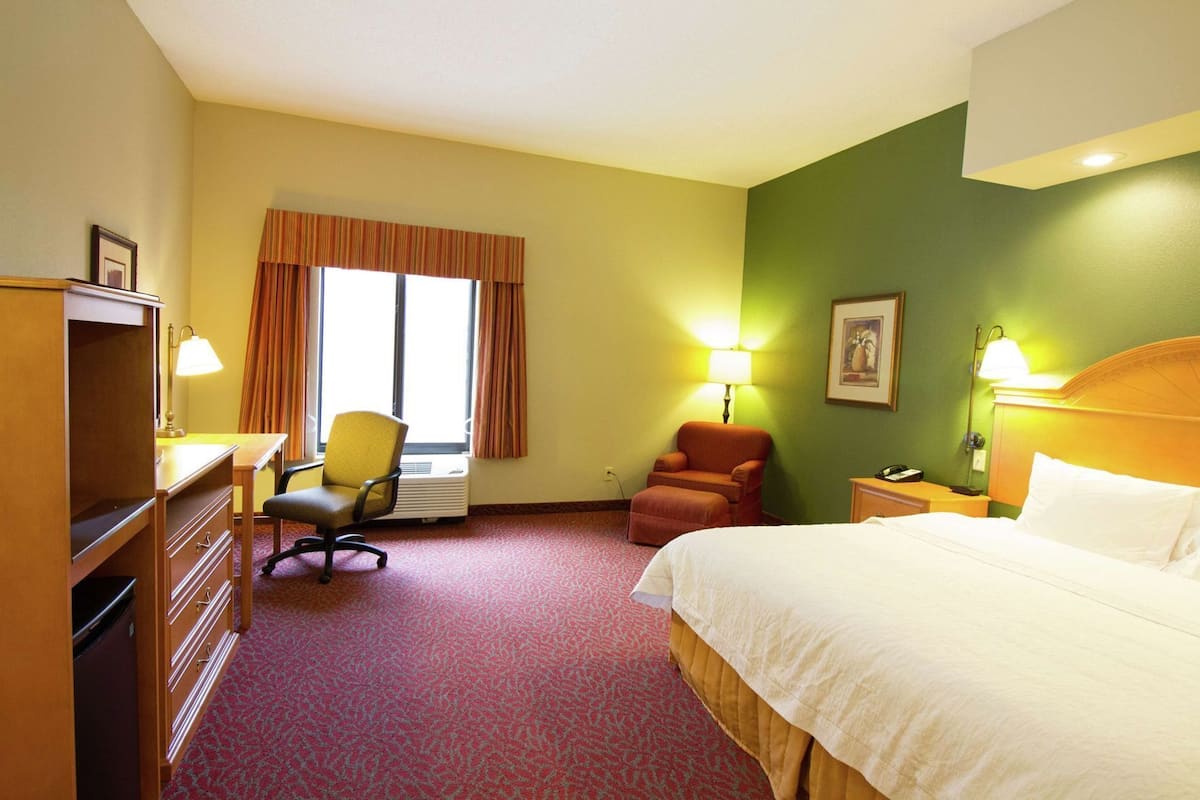 A hotel room with a bed, desk, chair, and two lamps.