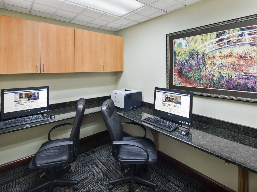 A workspace with two desks, two chairs, a printer, and a framed painting on the wall.