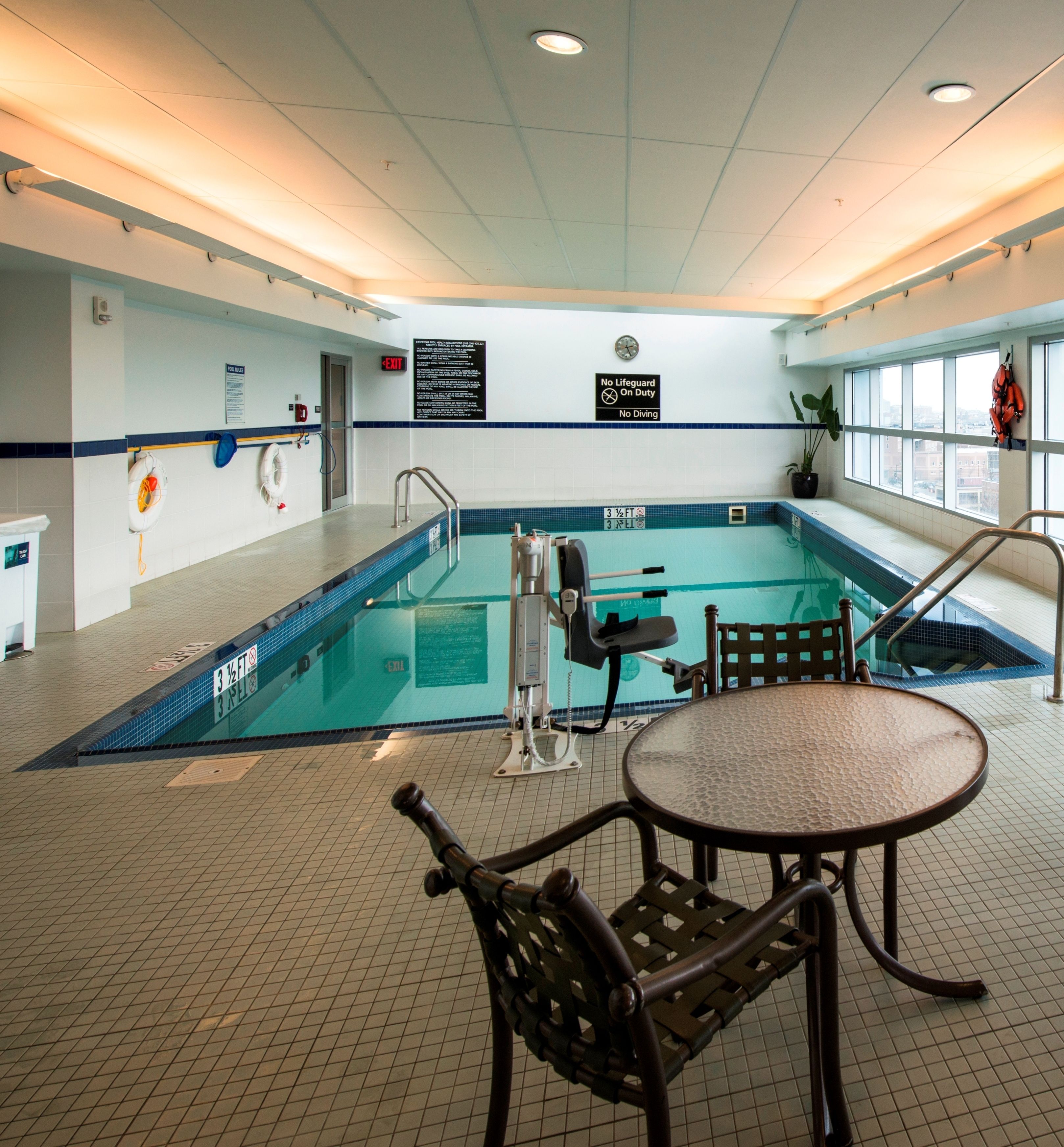 A swimming pool with a lifeguard chair, a table, and a chair in the center.