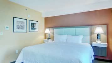 Habitación de hotel con una cama grande, dos mesitas de noche con lámparas y dos cuadros en la pared.
