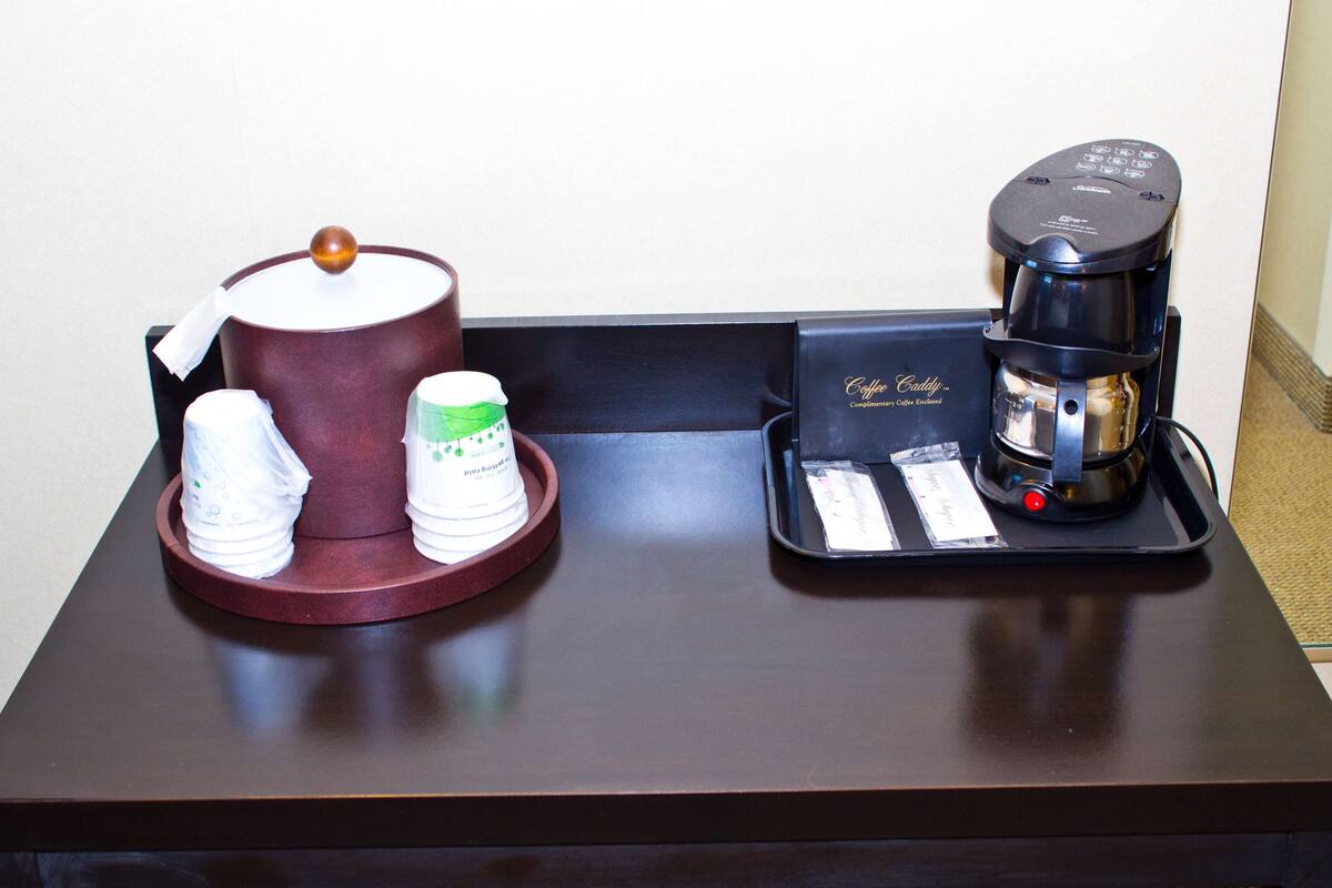 Angolo caffè con una macchina da caffè, un montalatte e due tazze su un vassoio.