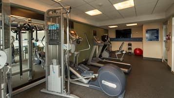 A gym with various exercise equipment including treadmills, elliptical machines, and weight machines.