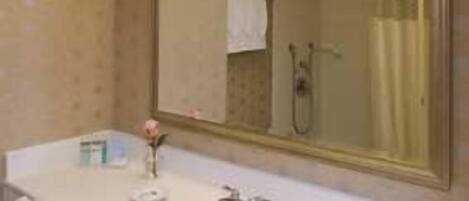 Un baño con lavamanos blanco, un espejo y cortina de ducha.
