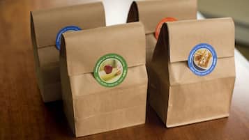 Three brown paper bags with logos on them, placed on a wooden surface.