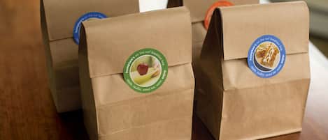 Three brown paper bags with logos on them, placed on a wooden surface.