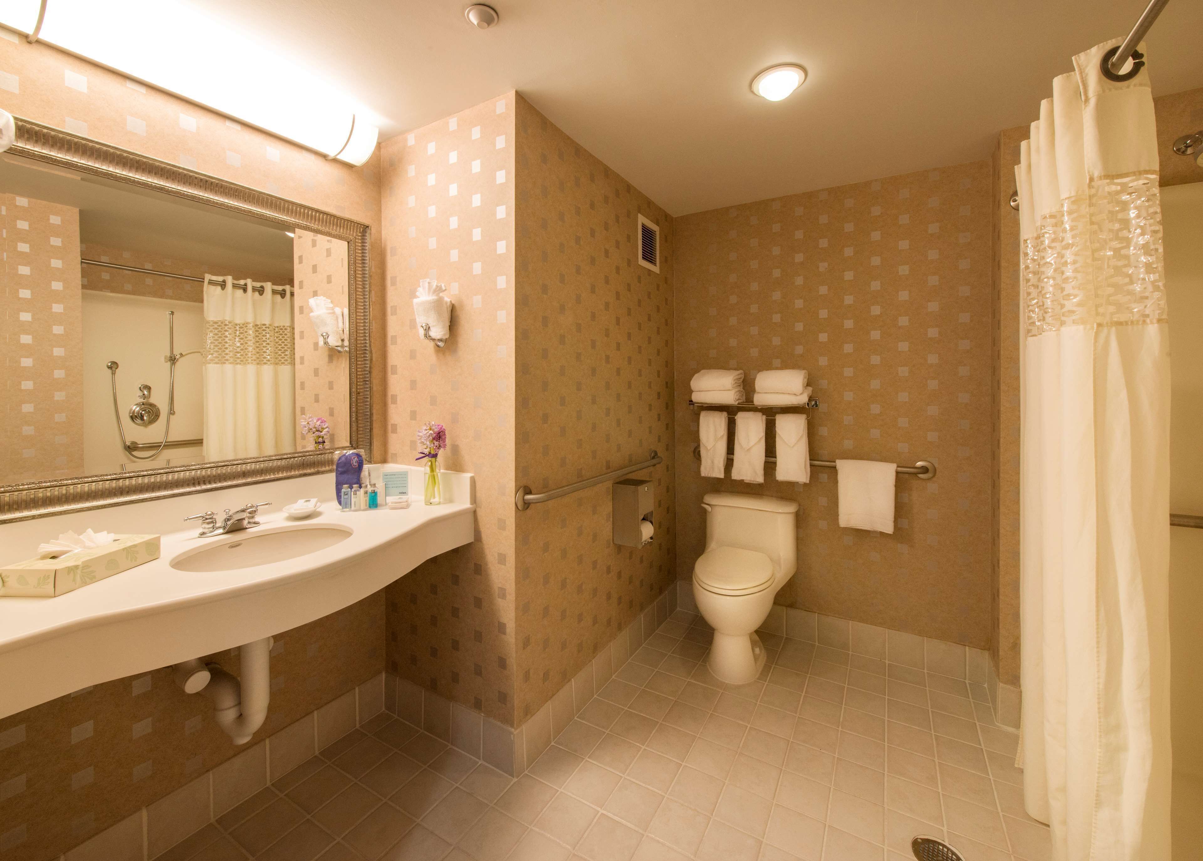 A bathroom with a sink, mirror, toilet, shower, and towel rack.
