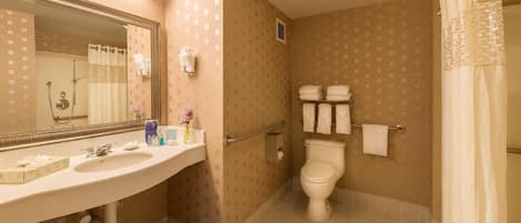 A bathroom with a sink, mirror, toilet, shower, and towel rack.