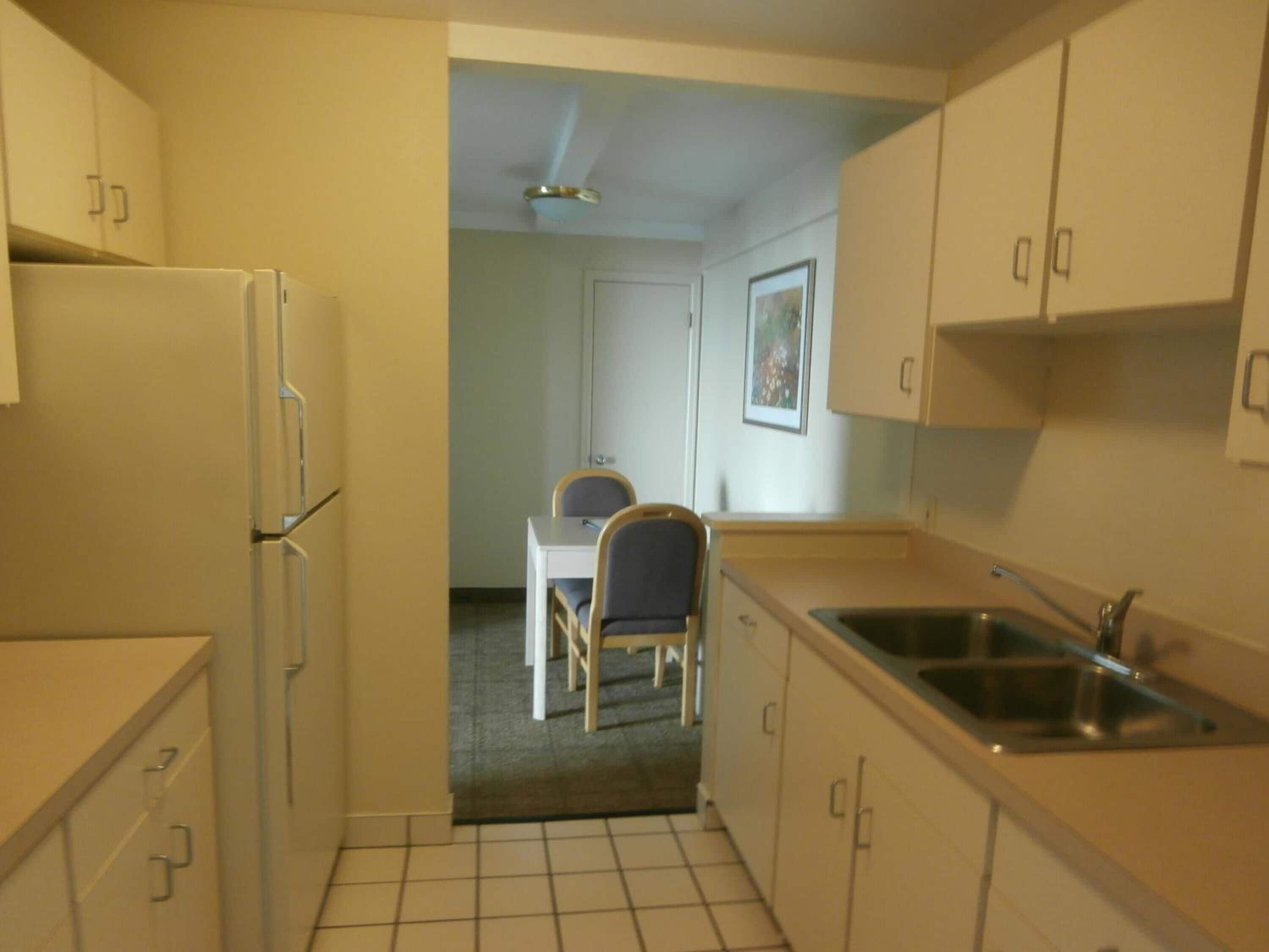 A compact kitchen with a refrigerator, sink, and a dining area with a table and chairs.