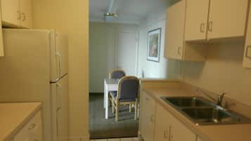 A compact kitchen with a refrigerator, sink, and a dining area with a table and chairs.