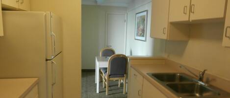 A compact kitchen with a refrigerator, sink, and a dining area with a table and chairs.