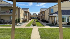 A covered walkway leading to a row of townhouses with balconies and a central lawn area. - Clinton Inn And Suites (Port Clinton)