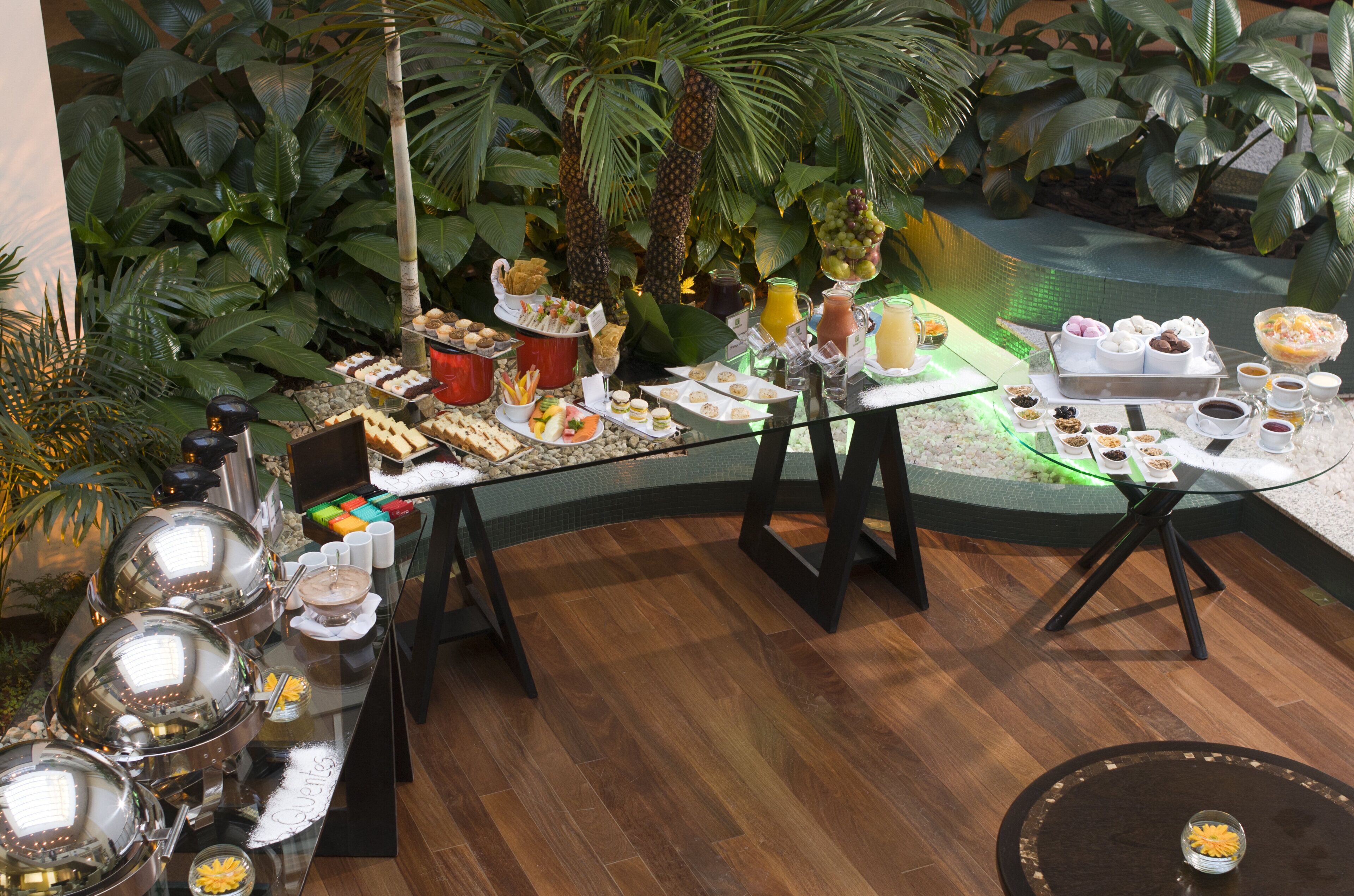 Ein reichhaltiges Buffet mit verschiedenen Speisen und Getränken, umgeben von üppiger Vegetation.
