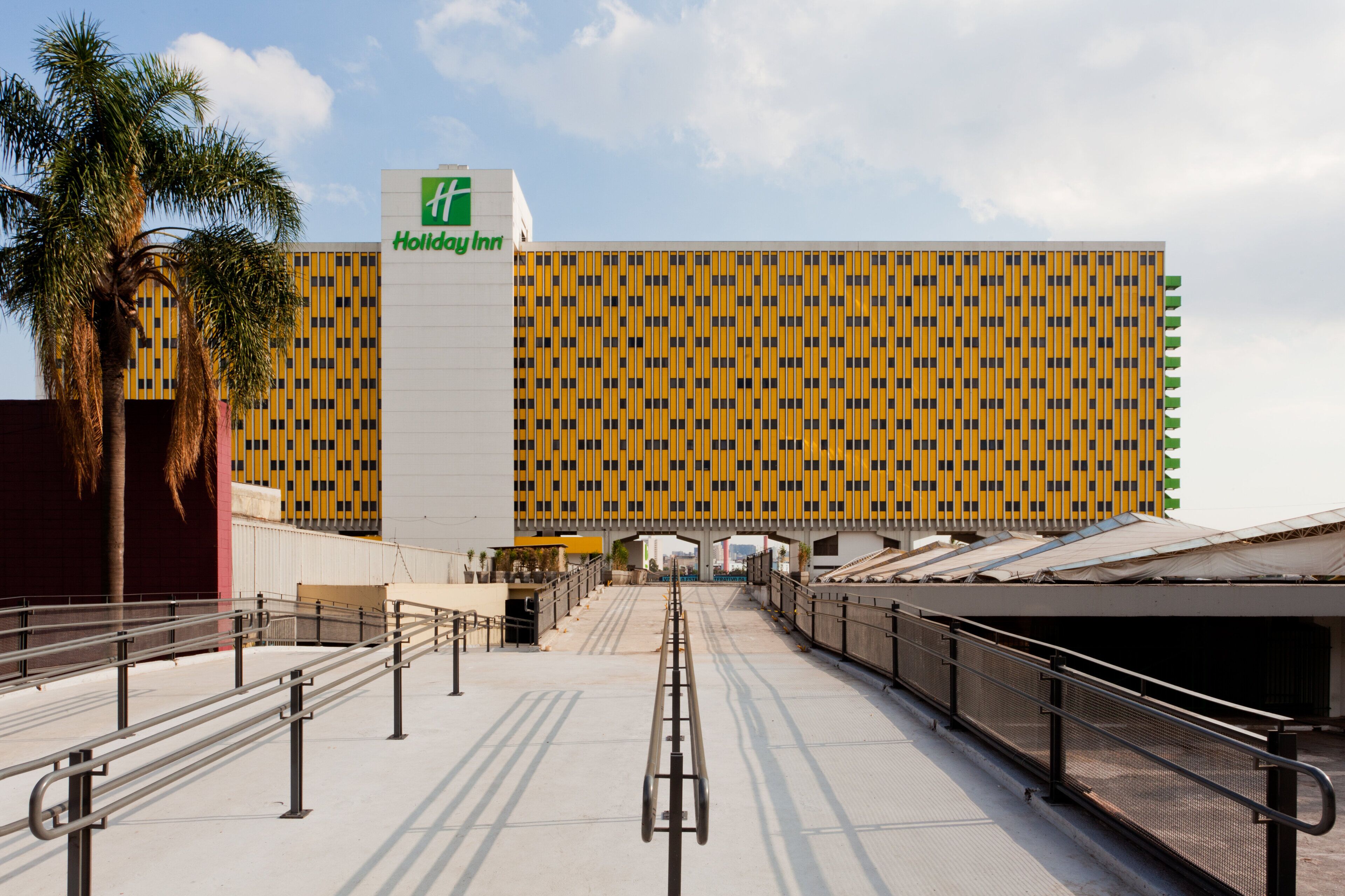 A Holiday Inn hotel with a yellow and black facade, a central entrance, and a covered walkway leading to the building.