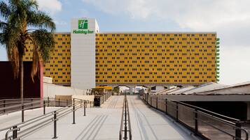 A Holiday Inn hotel with a yellow and black facade, a central entrance, and a covered walkway leading to the building.