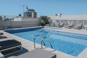 A rooftop pool with lounge chairs and a clear view of the city skyline. - Plaza Real Suites Hotel (Rosario)