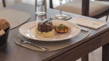 Una mesa de comedor con un plato de comida, una botella y una copa de vino.