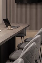 Una sala de conferencias moderna con una larga mesa, una computadora portátil y una taza.