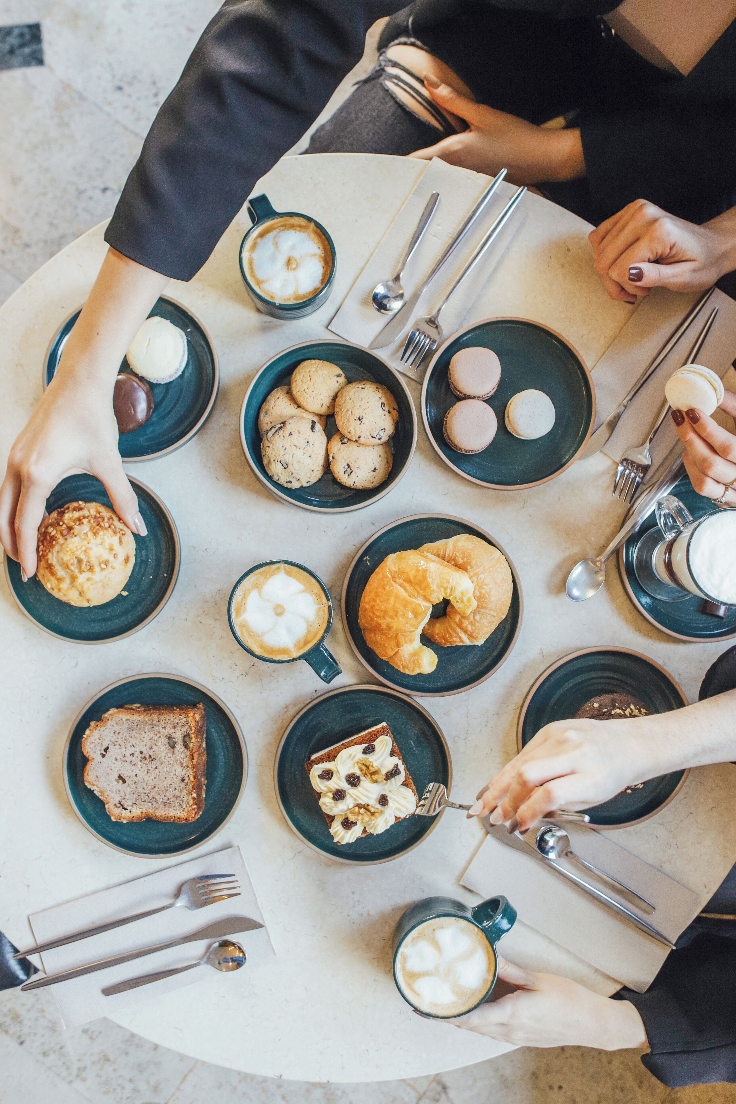 Una mesa con diferentes alimentos y utensilios, como pasteles, galletas y café.