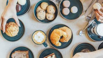 Una mesa con diferentes alimentos y utensilios, como pasteles, galletas y café.