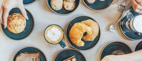 A table with various food items and utensils, including pastries, cookies, and coffee.