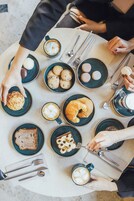 Una mesa con diferentes alimentos y utensilios, como pasteles, galletas y café.
