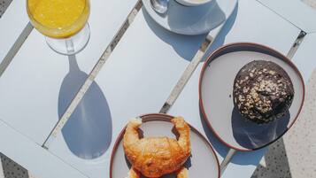 Una tavola con un croissant, un muffin, caffè e succo d'arancia.