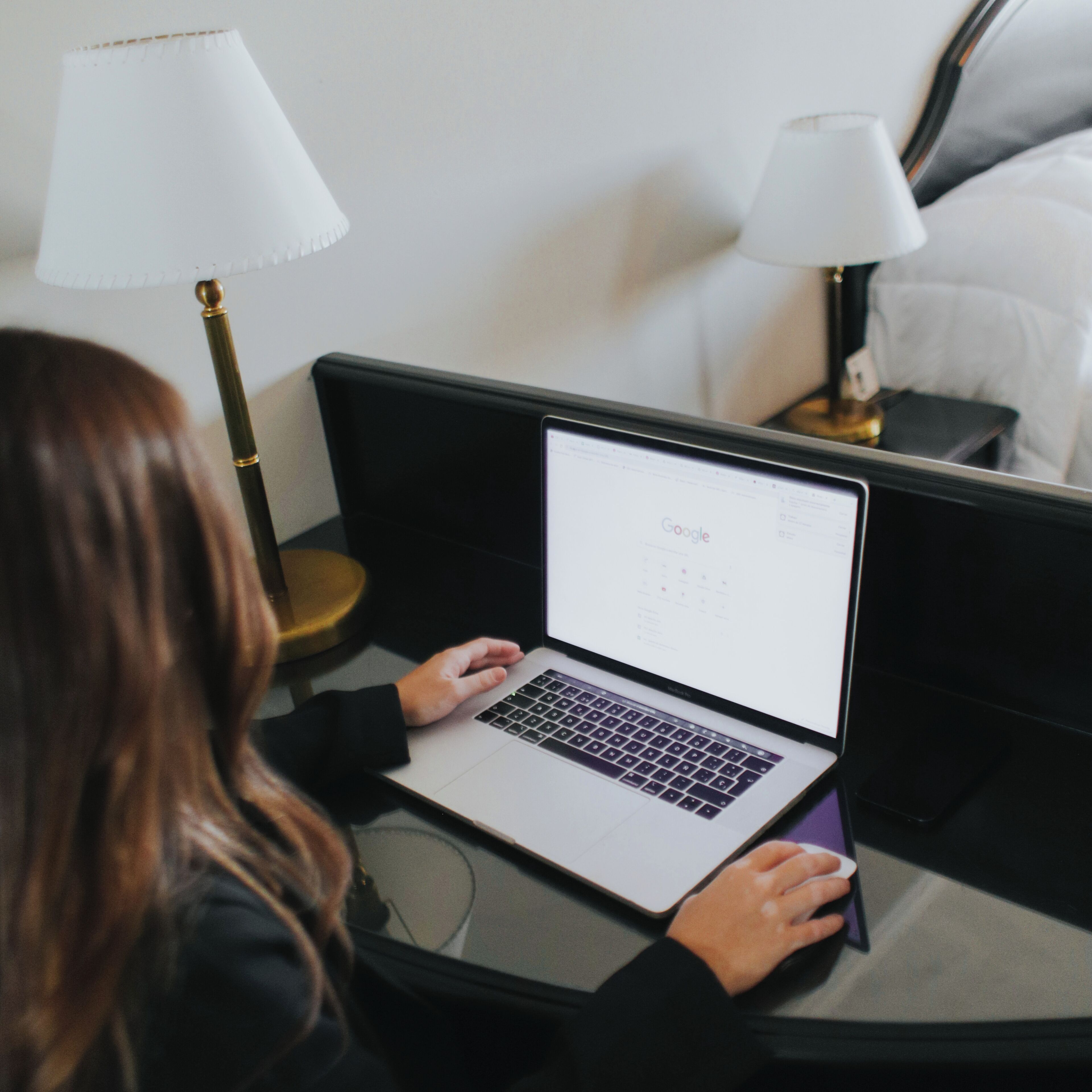 A person using a laptop on a bed in a hotel room.