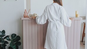 Eine Person in einem weißen Bademantel steht an der Rezeption, über ihr befindet sich ein Schild mit den Aufschriften 'gimnasio' und 'piscina'.