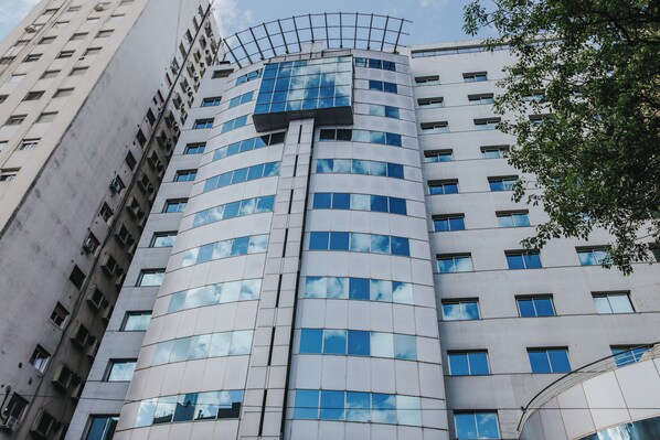 A modern building with a curved facade, multiple windows, and a rooftop terrace. - Plaza Real Suites Hotel (Rosario)