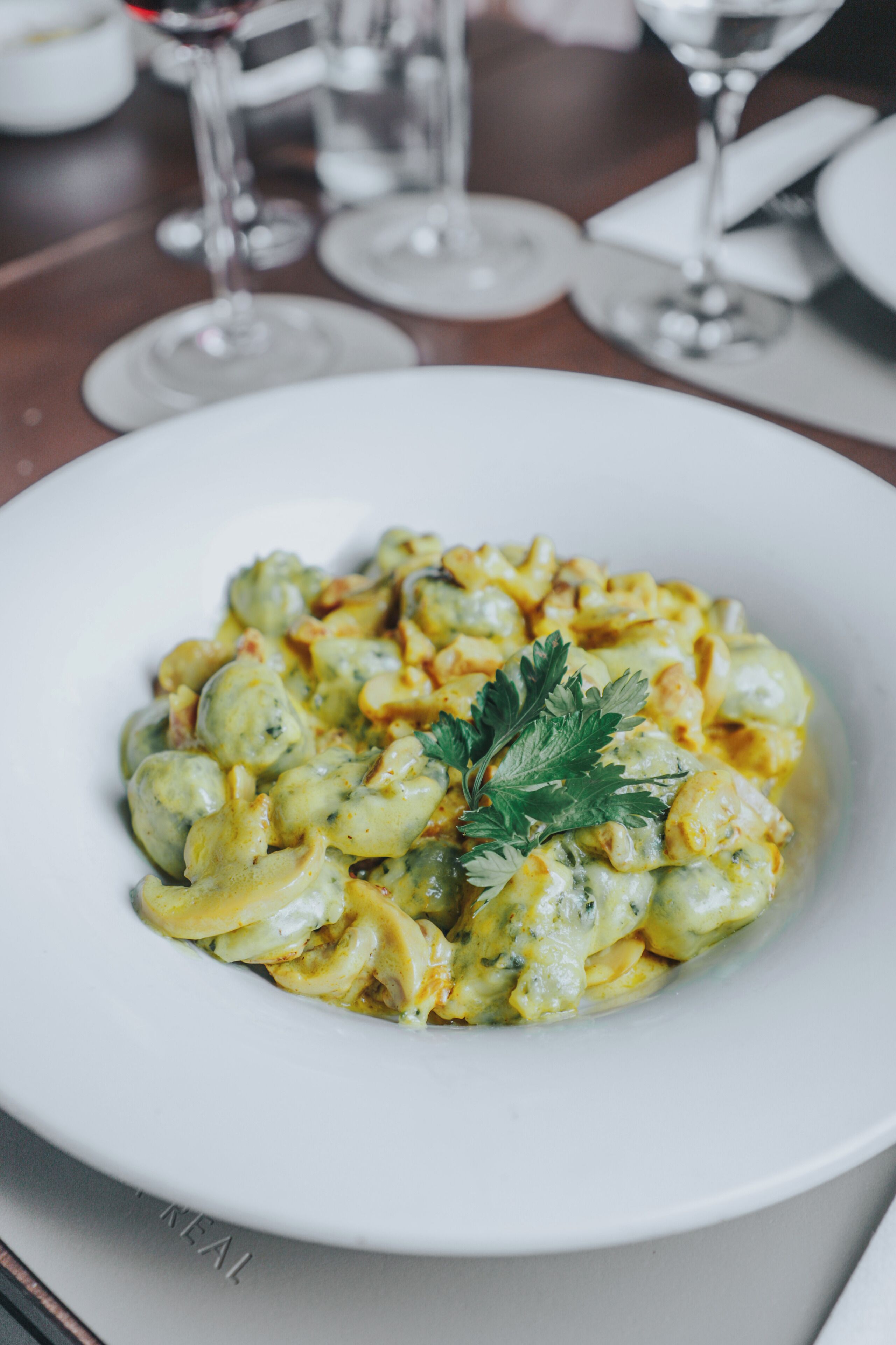 A white plate of pasta with a garnish on a table.