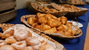 Une table de buffet proposant divers produits de boulangerie, notamment des croissants et des pâtisseries, présentés dans des paniers.