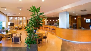Een hotel lobby met een receptiebalie, een zithoek en een groot raam.