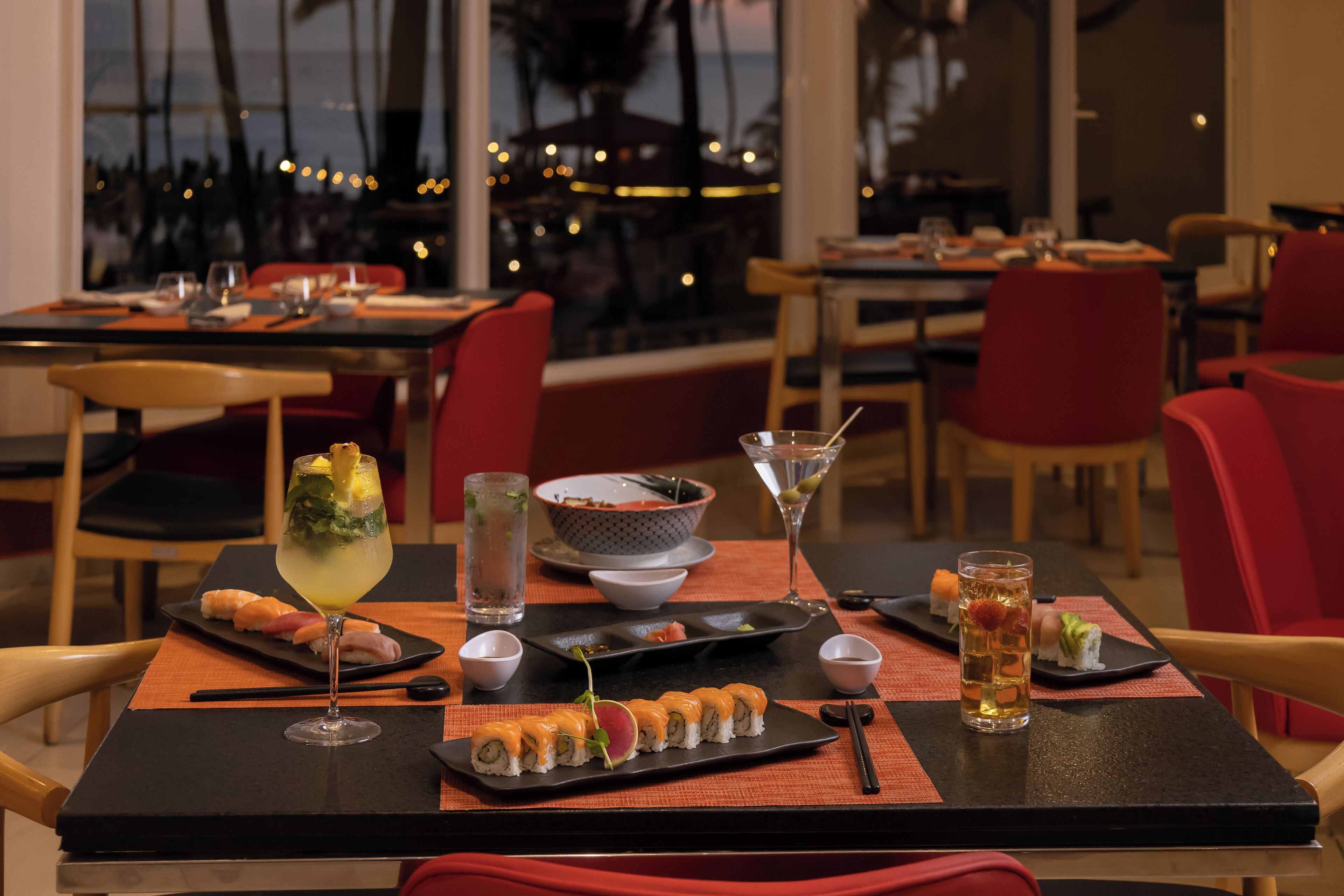Un ristorante con piatti di sushi, bevande e vista sull'oceano.