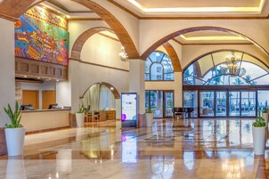 Un hallo espacioso con techos abovedados, una mesa de recepción y grandes ventanales que ofrecen vistas al exterior.